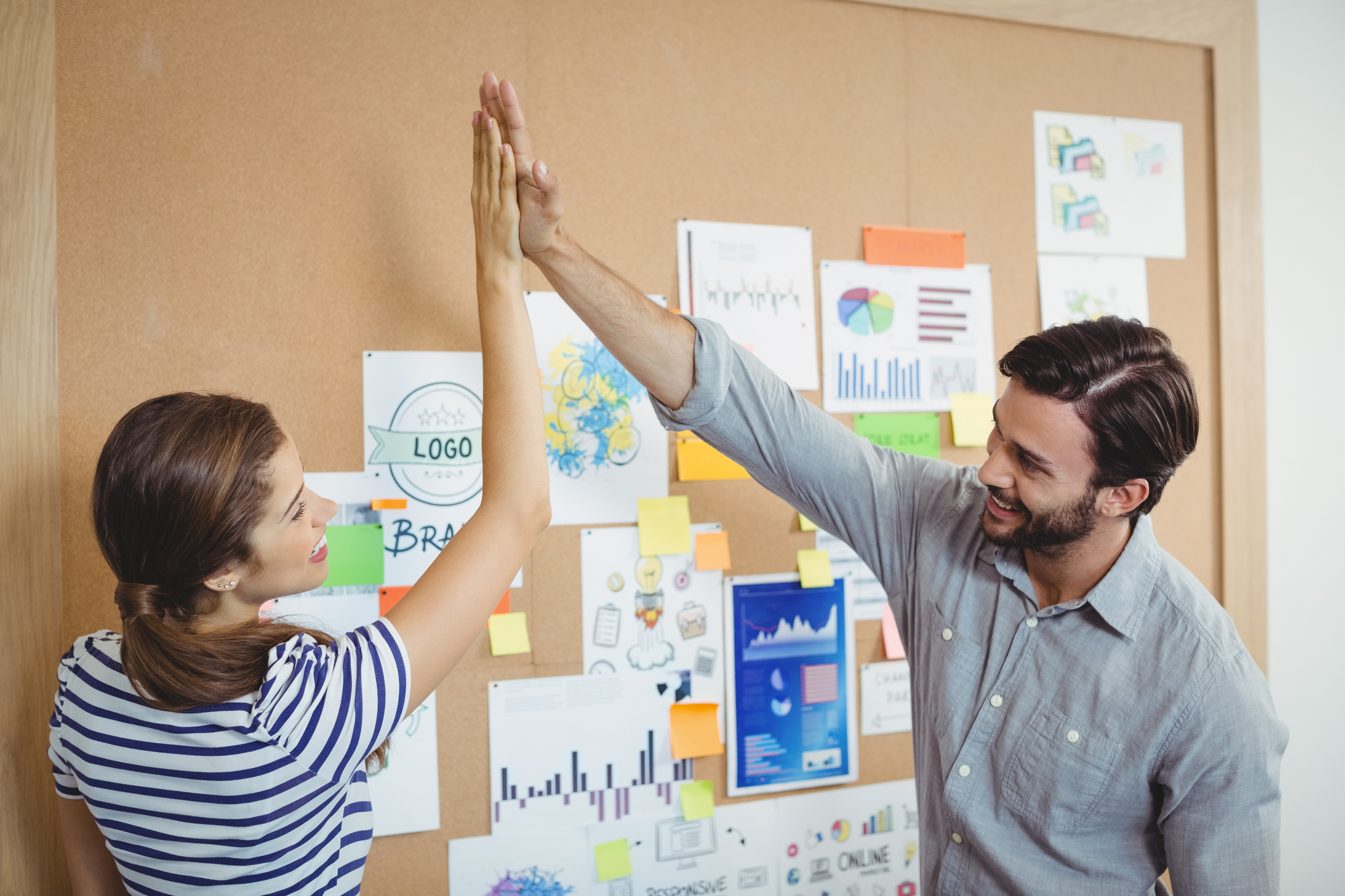 Male and female executives giving high five to each other in office